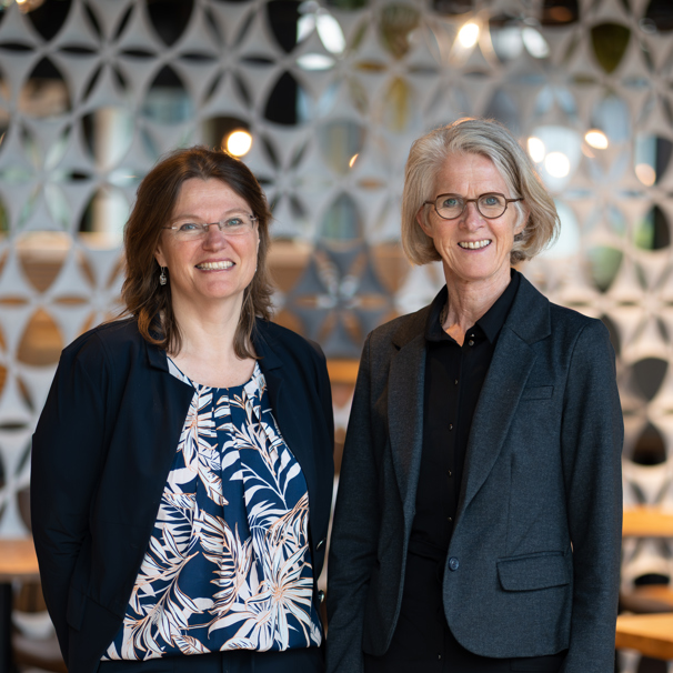 Bestuurders Astrid van der Put en Thea Sijbesma staan naast elkaar en kijken lachend in de camera Raad van bestuur Anna Zorggroep